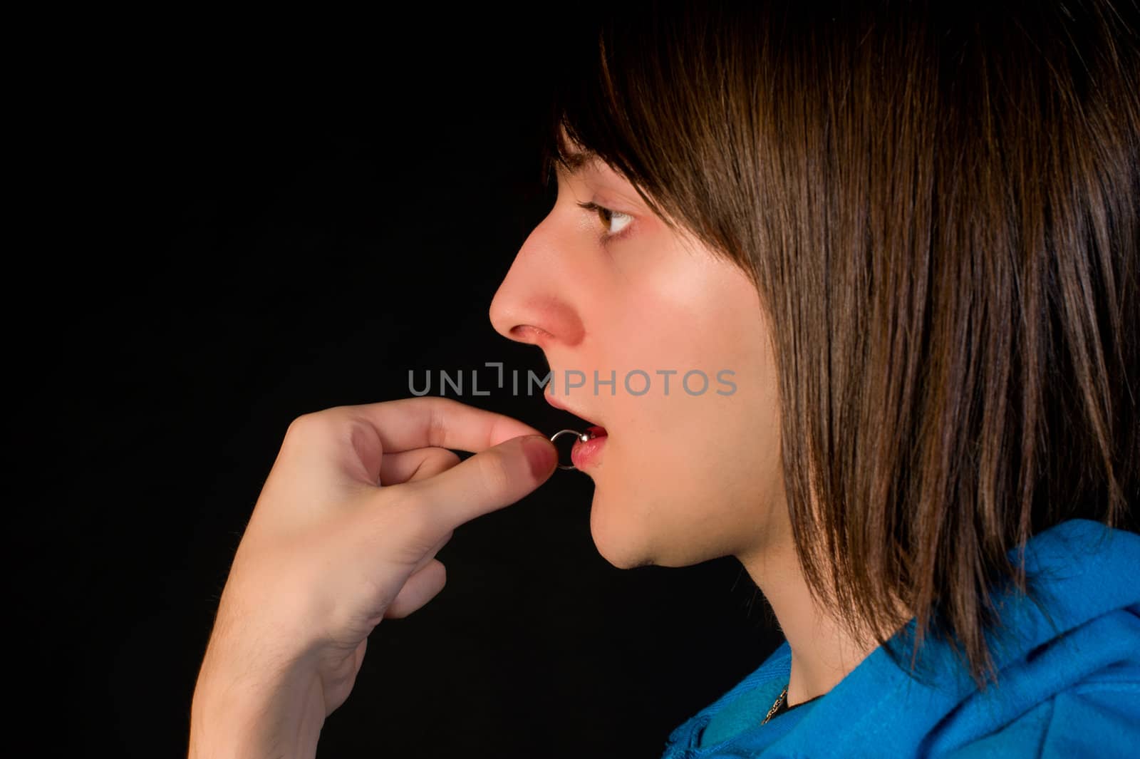 Teenager putting on his silver lip ring piercing