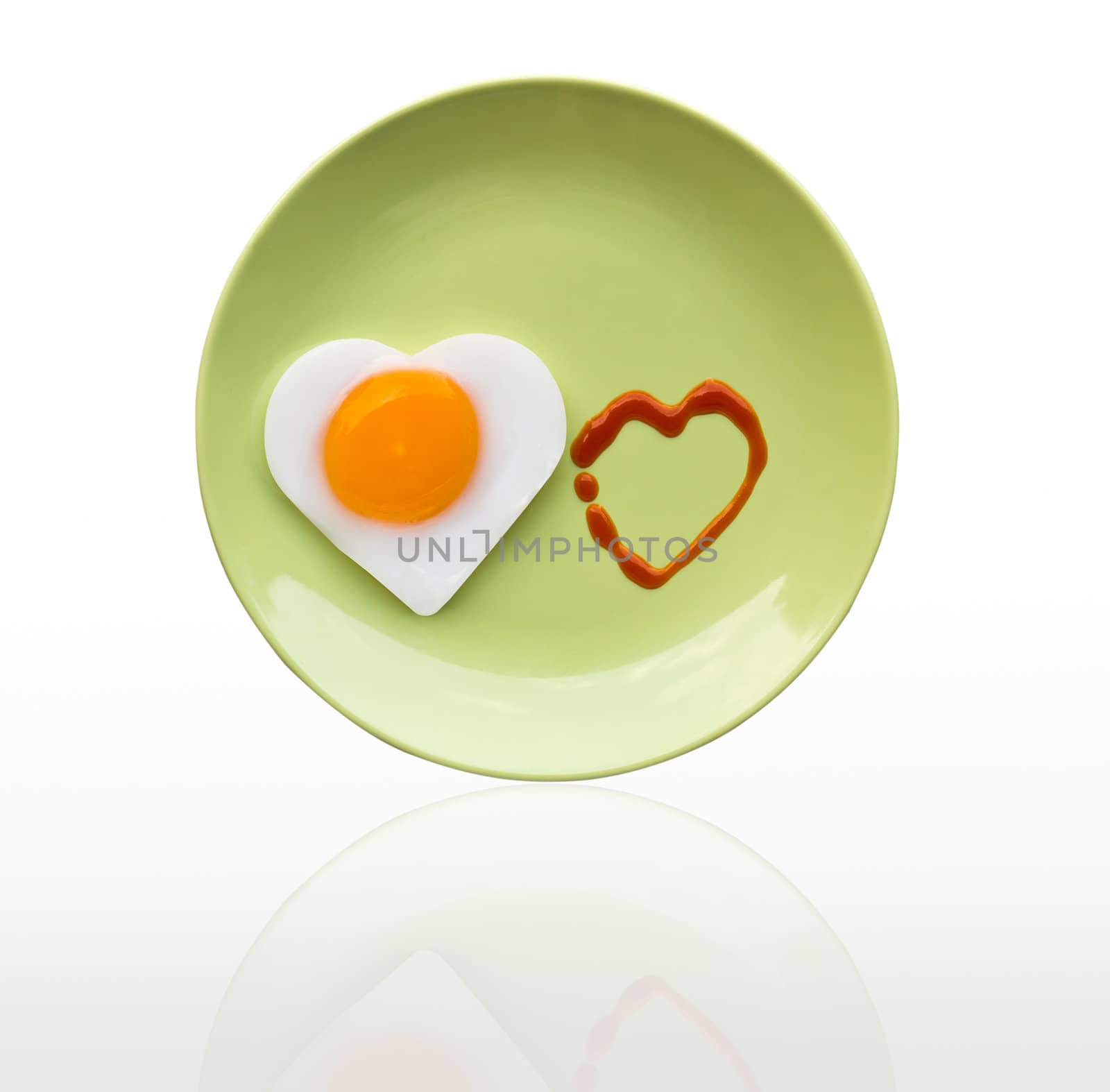 Fried egg heart and source heart on green dish