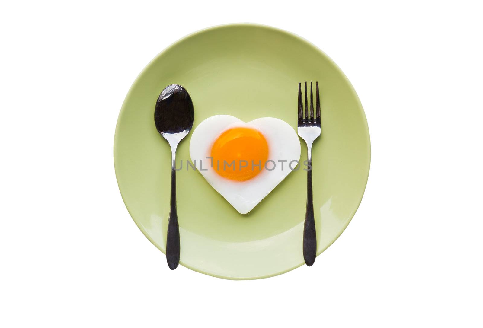 Fried egg heart and spoon on green dish