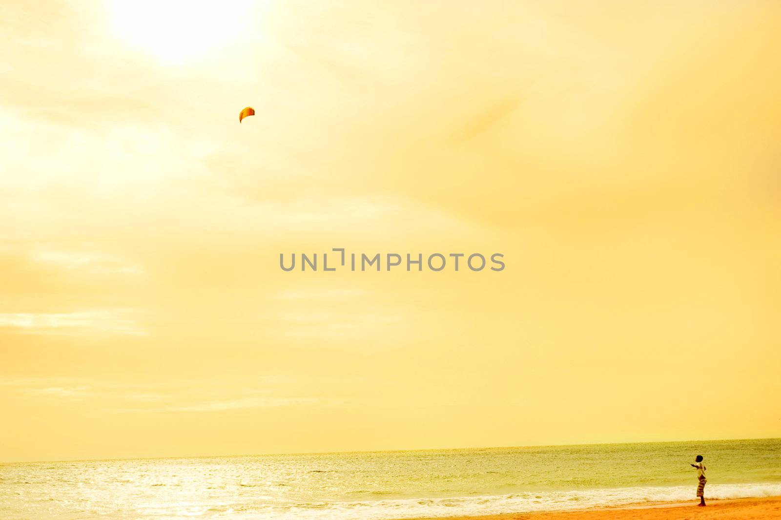 Boy playing wtih flying kite on the ocean beach. Sri Lanka