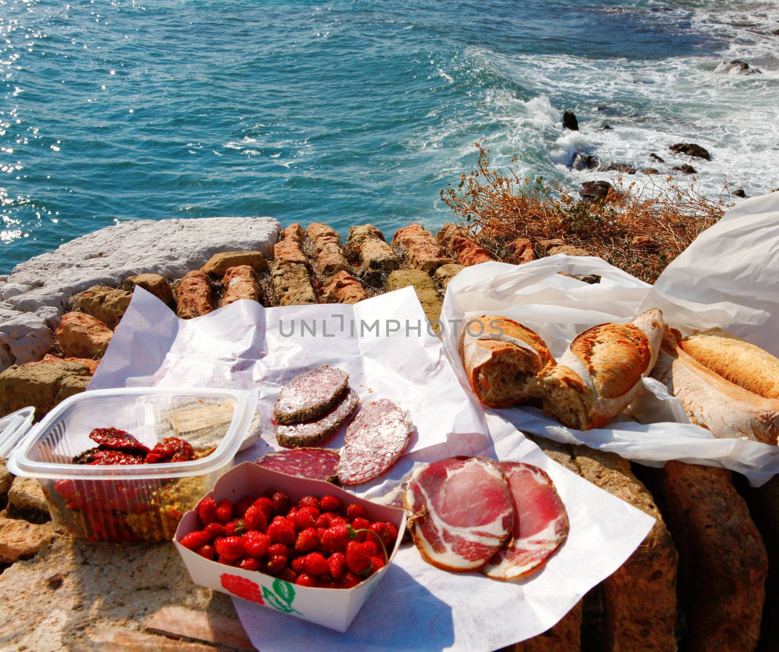 French food picnic outdoors near sea with market food on the old brick wall.