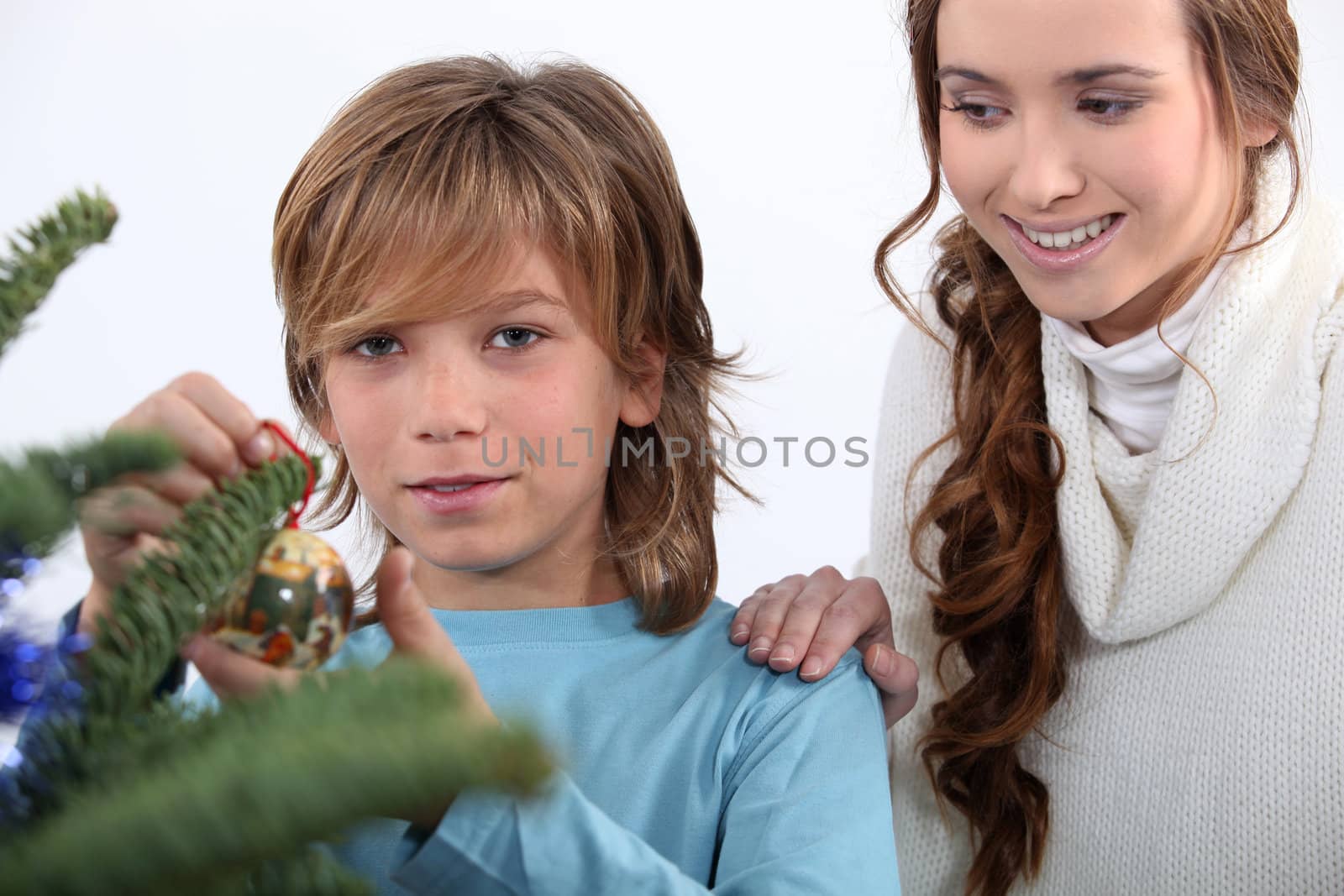 child decorating Christmas tree by phovoir