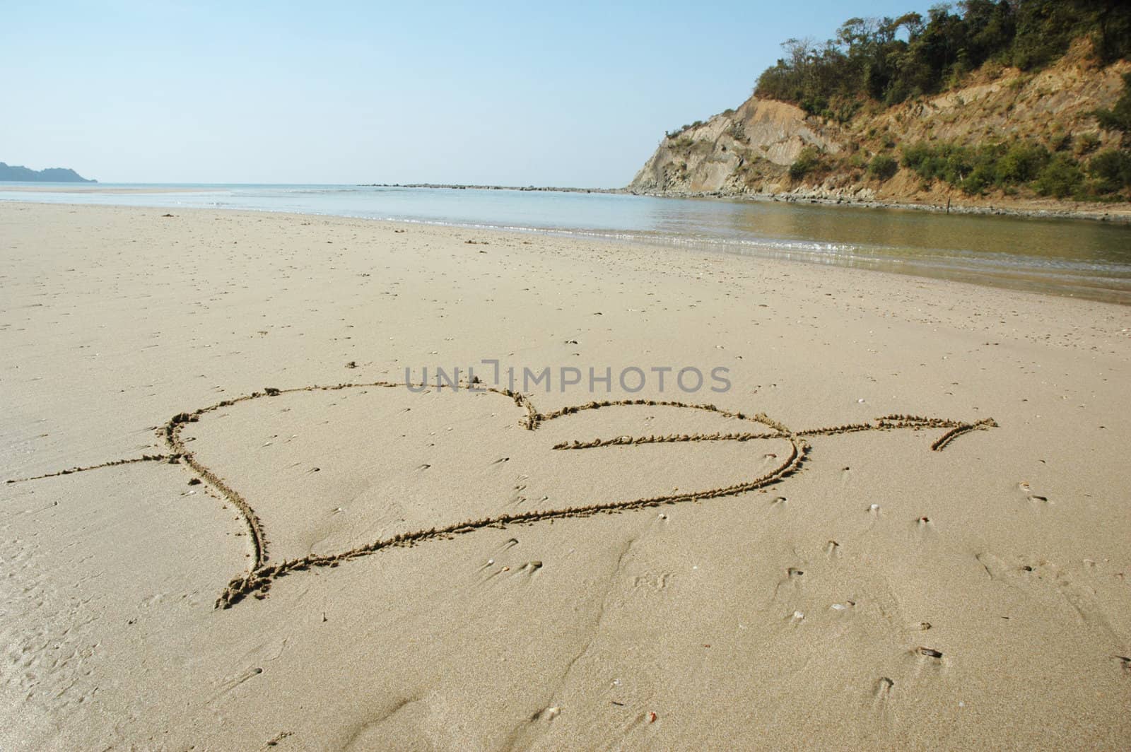 Heart with arrow shooting over drawn on a wet sandy beach