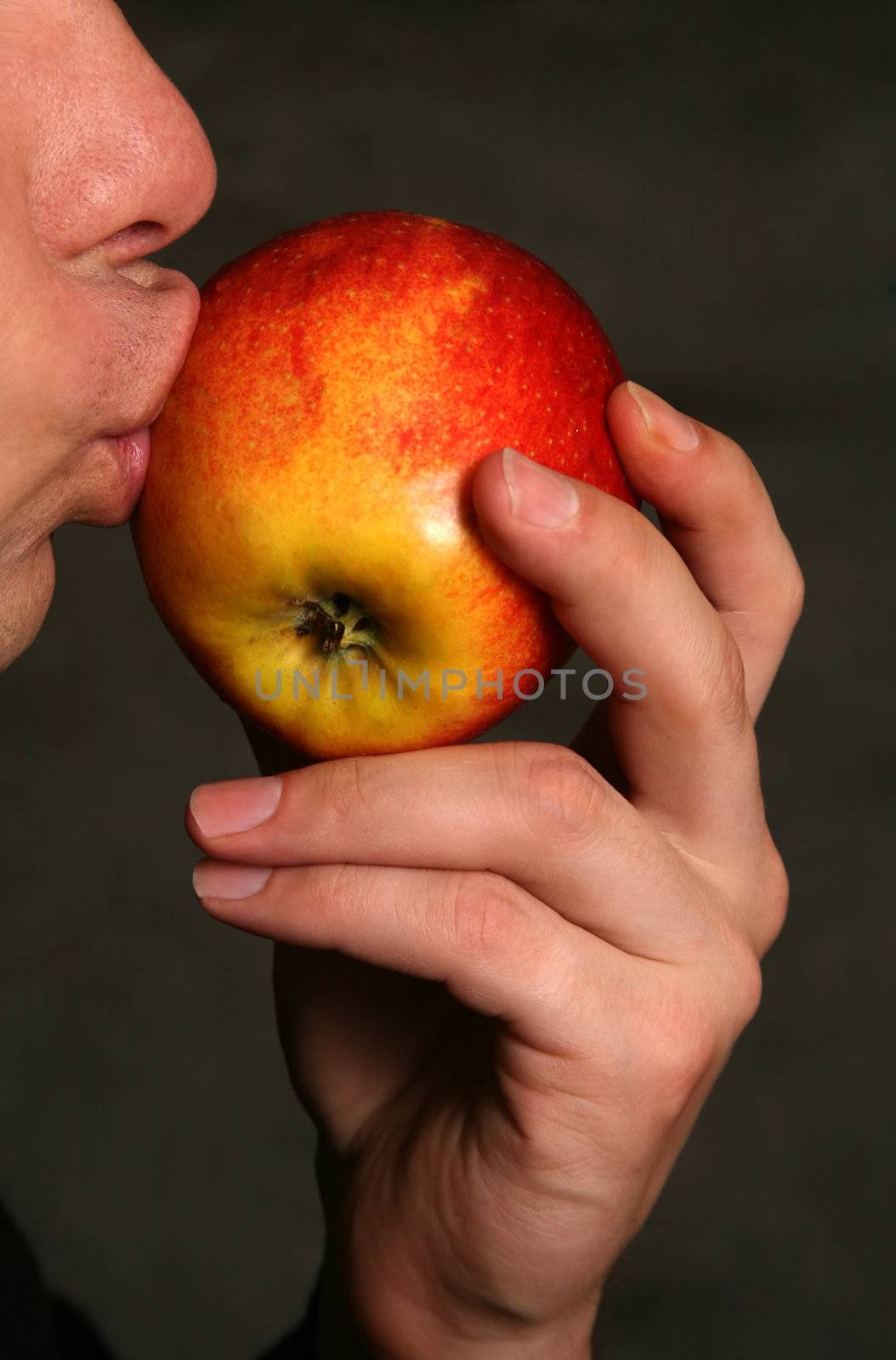 The man concerns lips of a red apple