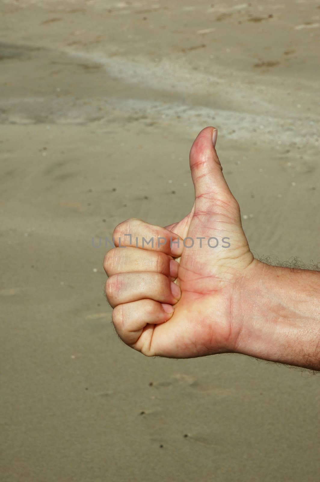 Thumb's up sign gesturing let's go against sandy beach background