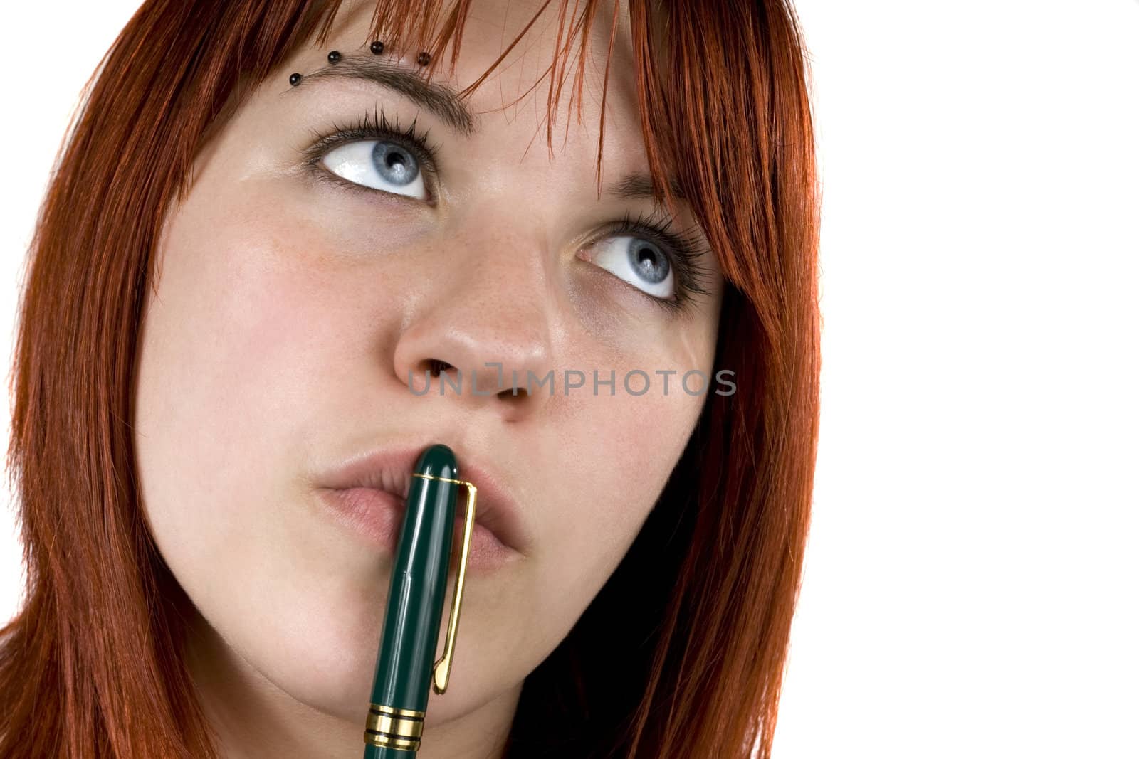 Cute girl with redhair pensive with pen on her lips.