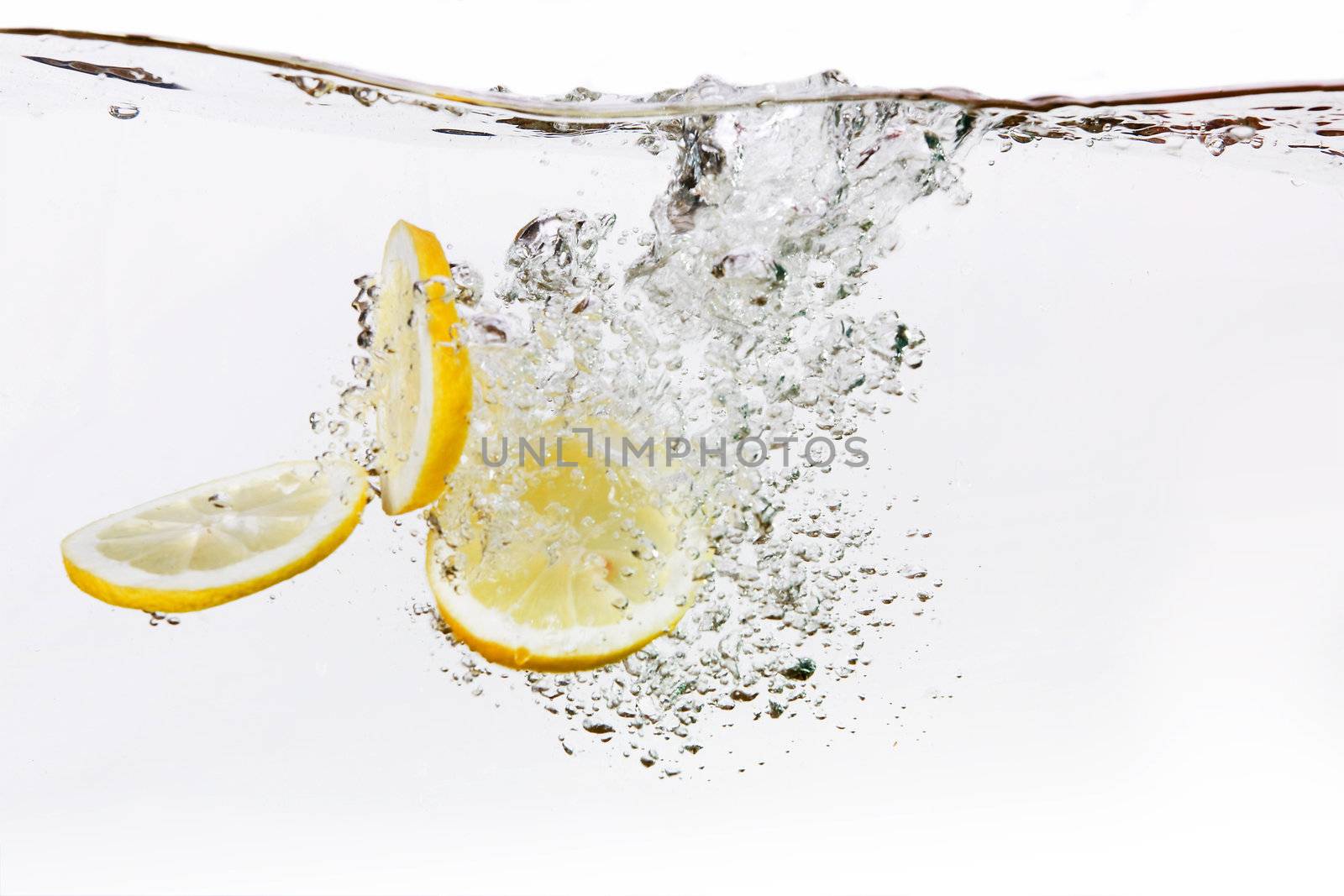 A group of lemon slices dropped in water with bubbles