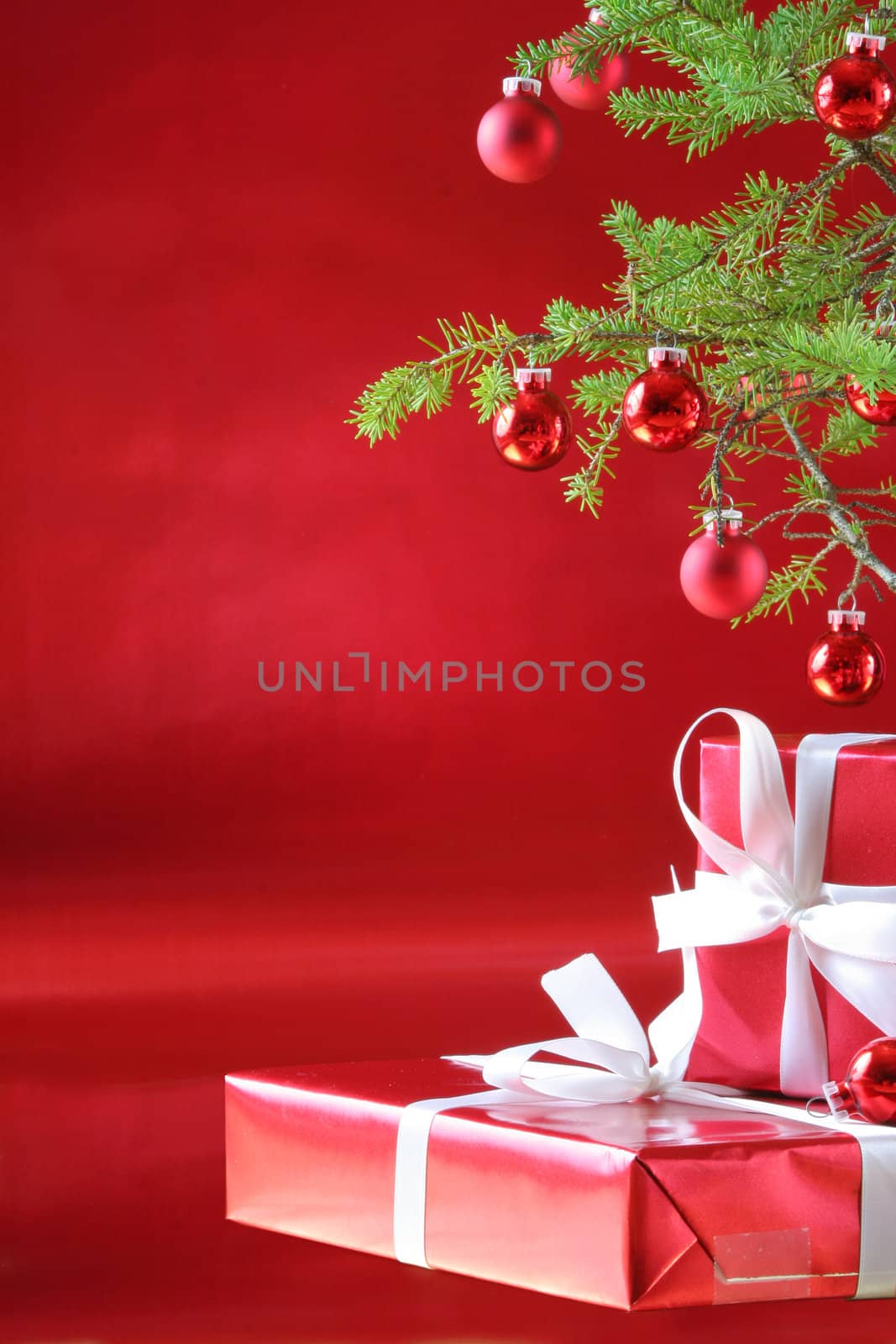 Elegant red presents under Christmas tree with deep rich red background.