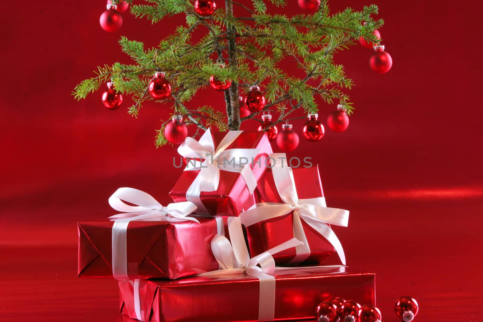 Elegant red presents under Christmas tree with deep rich red background.