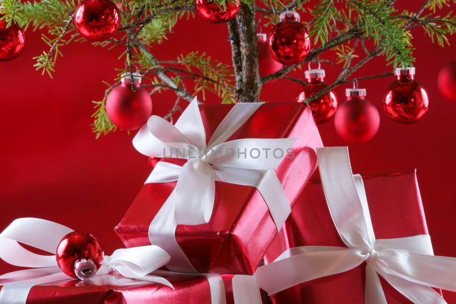 Elegant red presents under Christmas tree with deep rich red background.