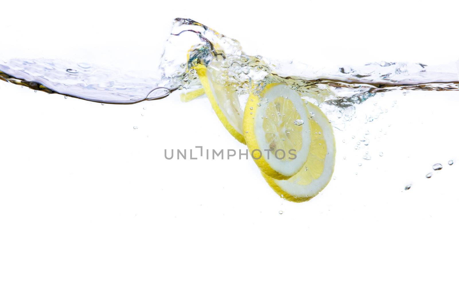A group of lemon slices dropped in water with bubbles