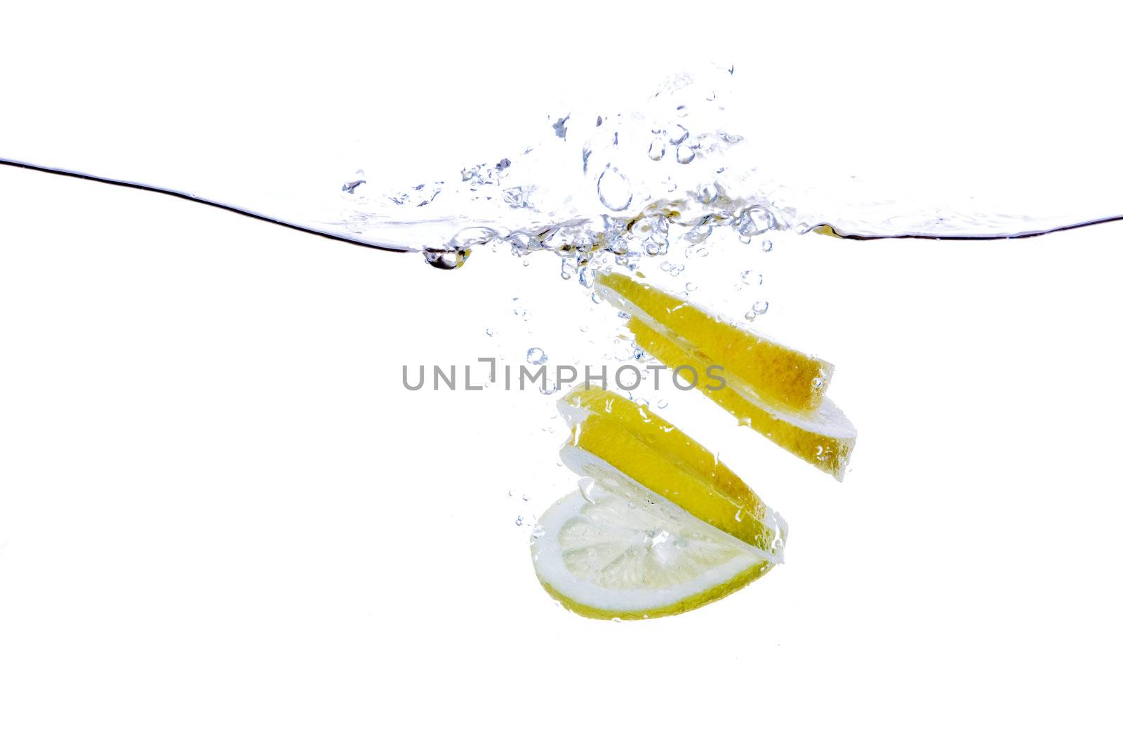 A group of lemon slices dropped in water with bubbles