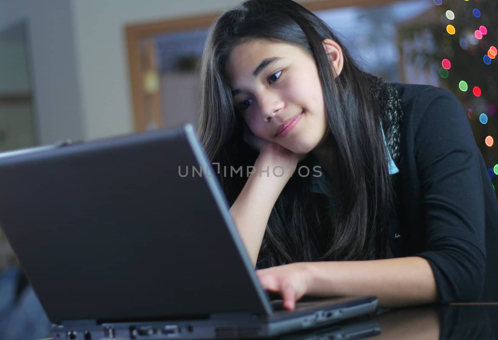 Young teen girl working on the laptop at night.
