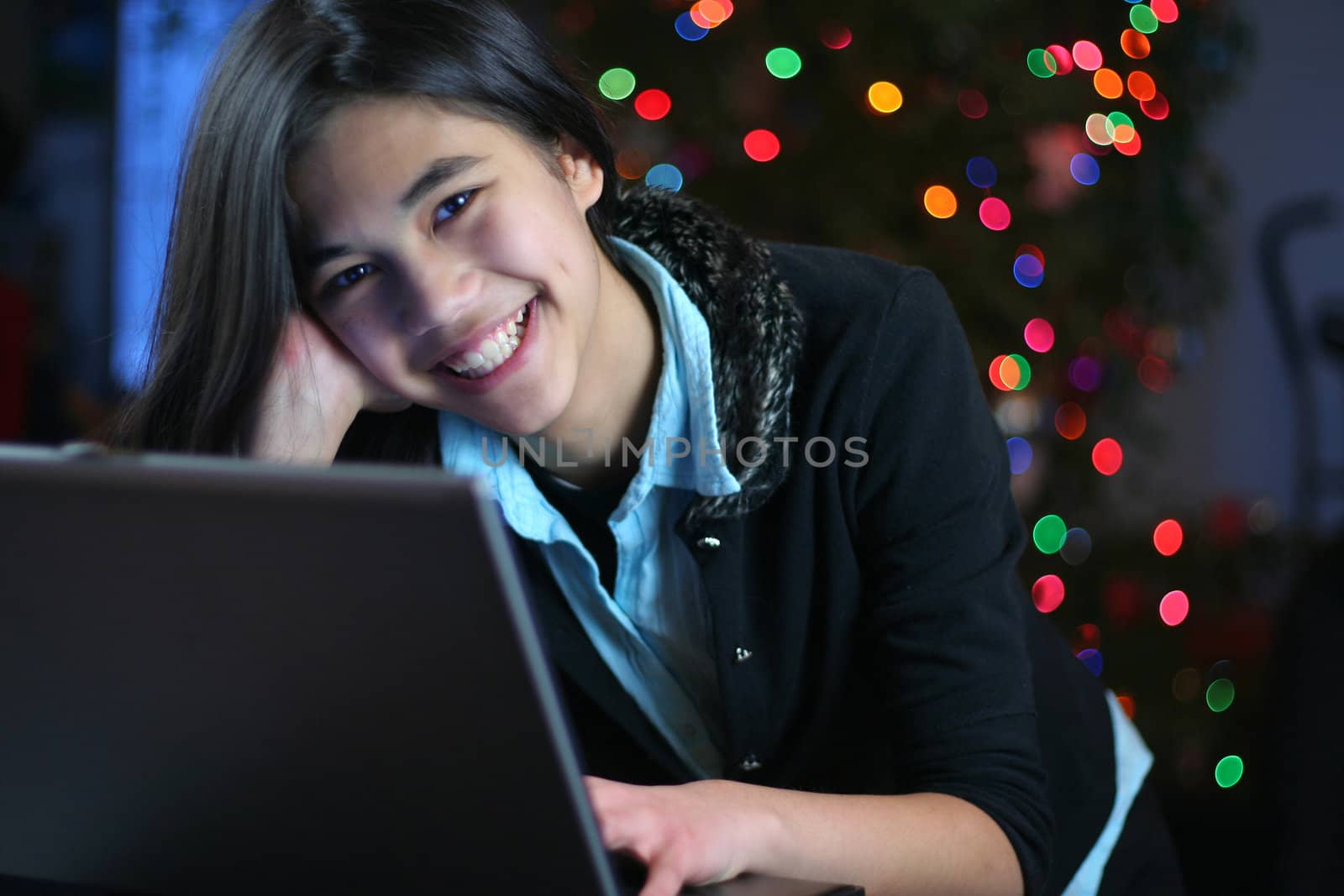 Young teen girl working on the laptop at night.