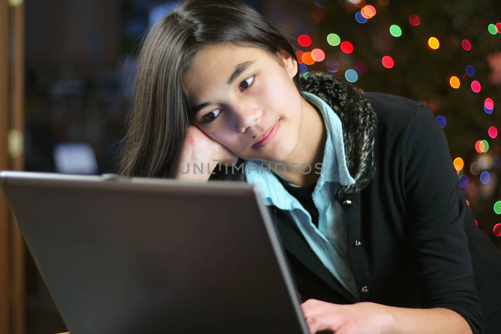 Young teen girl working on the laptop at night.