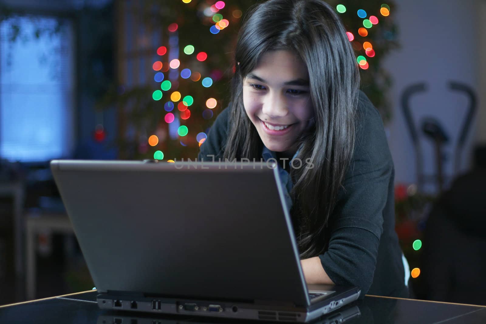 Young teen girl working on the laptop at night.