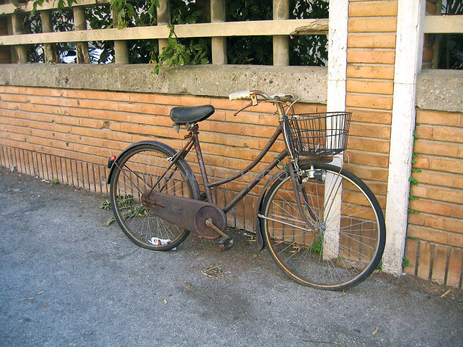 Old abandoned rusty city bicycle on brick wall