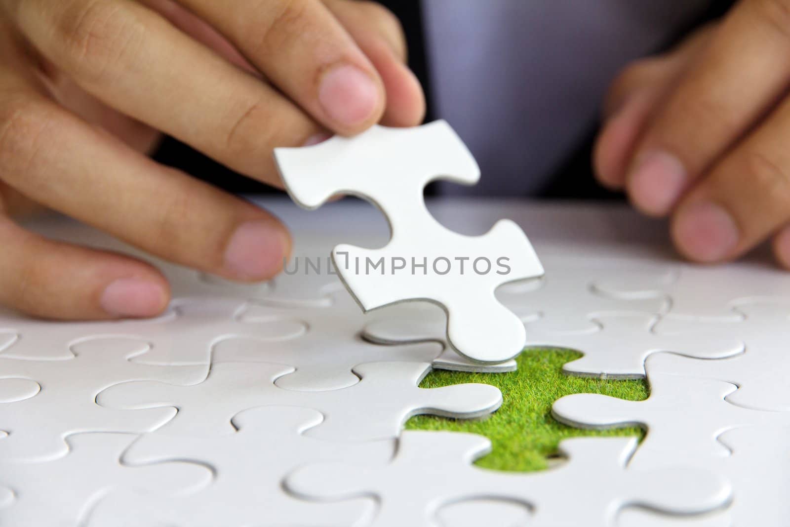 business man hand holding a puzzle piece, green space concept