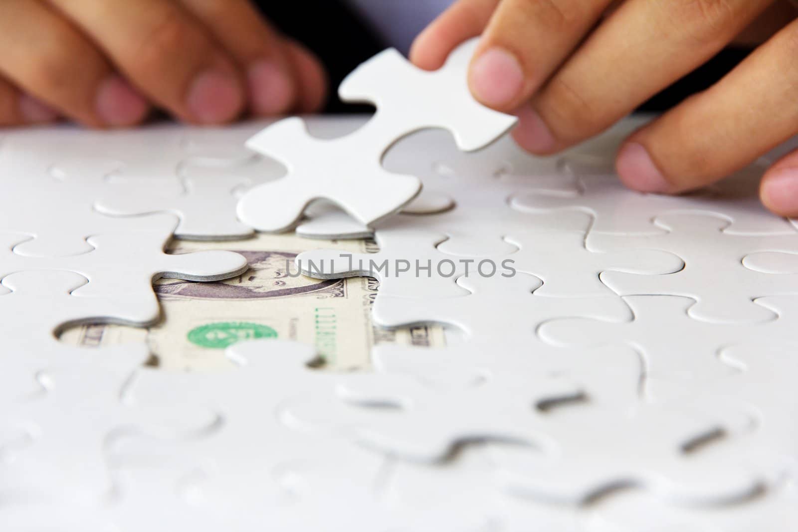 business man hand holding a puzzle piece, money concept by ponsulak