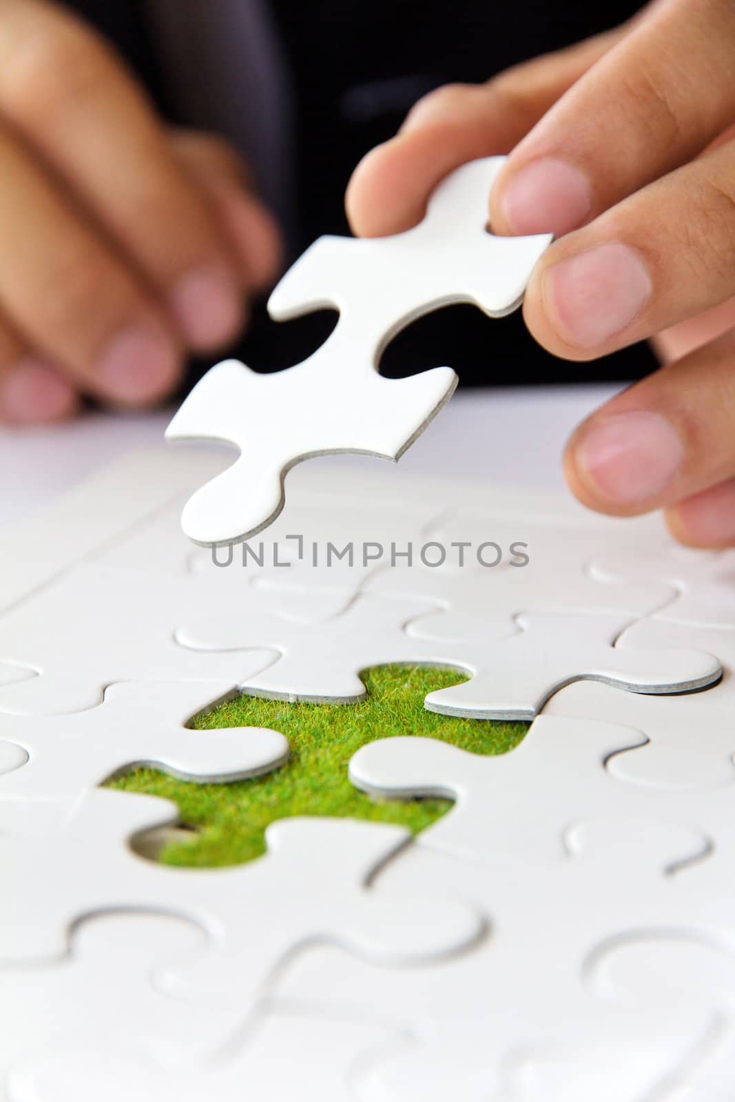 business man hand holding a puzzle piece by ponsulak