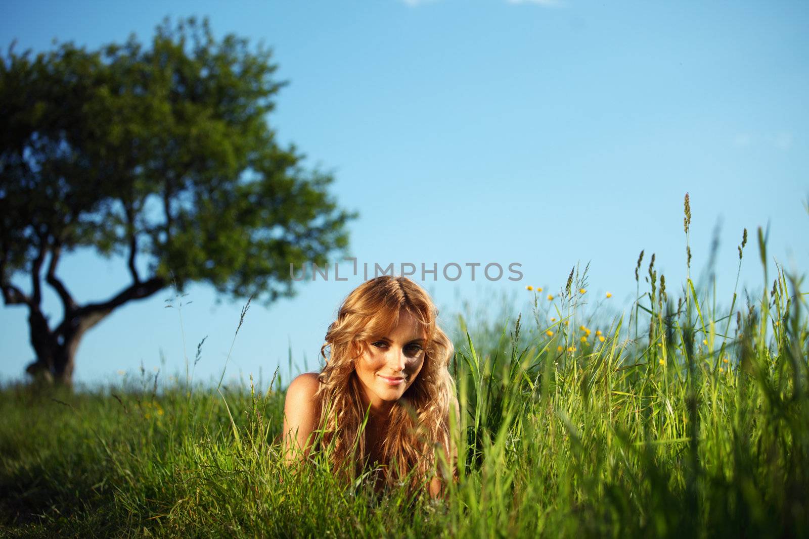 blonde lays under the tree 