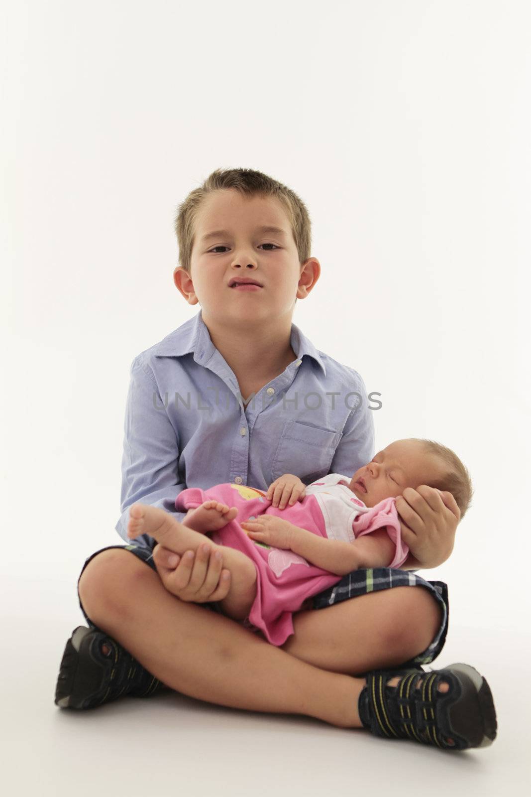 Mischievous boy holding newborn baby sister.