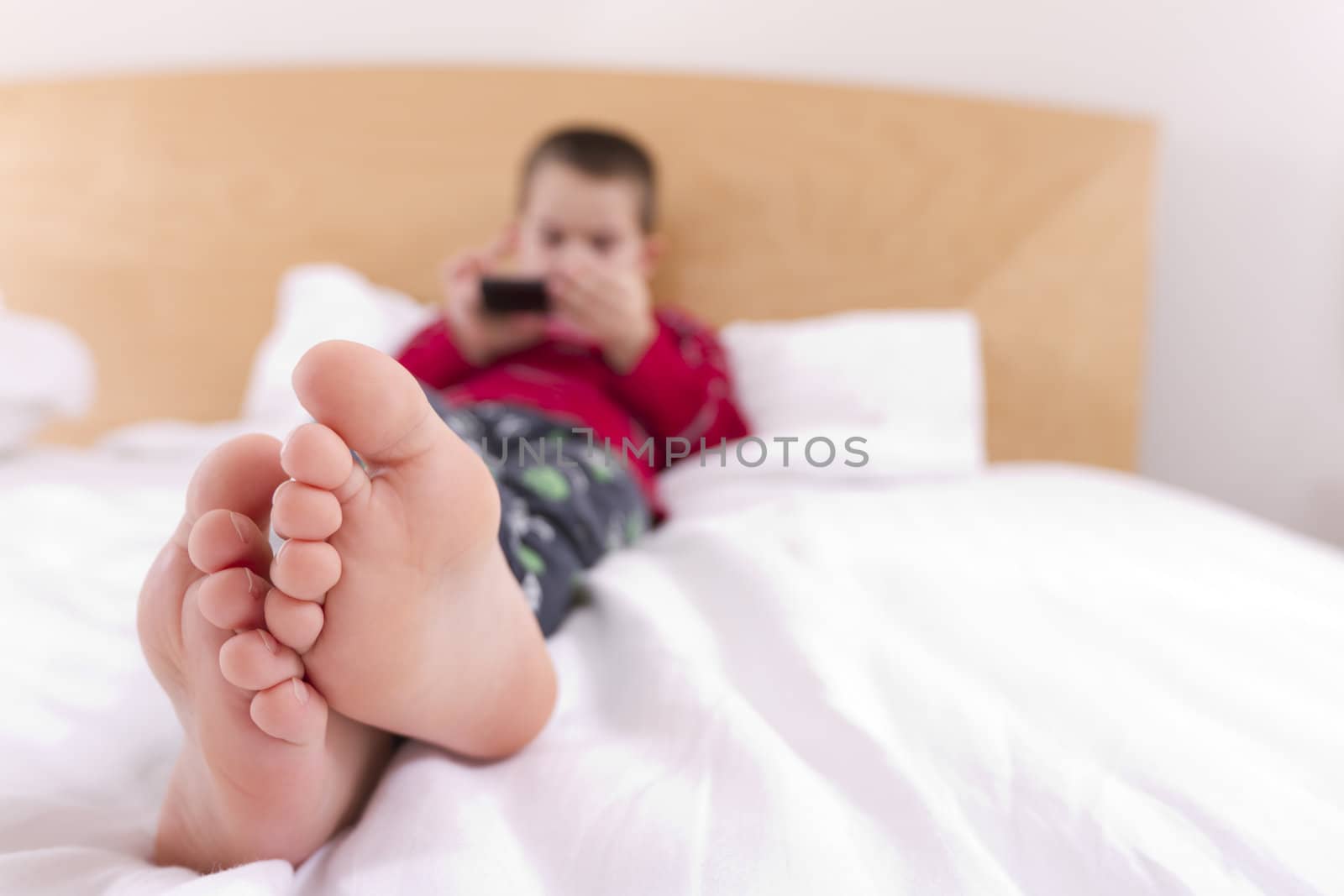A kid enjoying sunday morning texting with his phone.