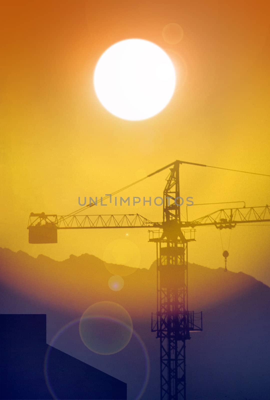 Crane on construction site back lit by sun