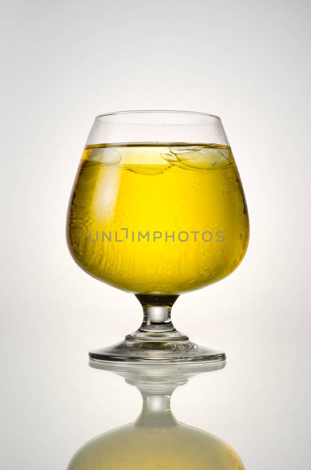 Beer and ice in glass with reflection on a white background