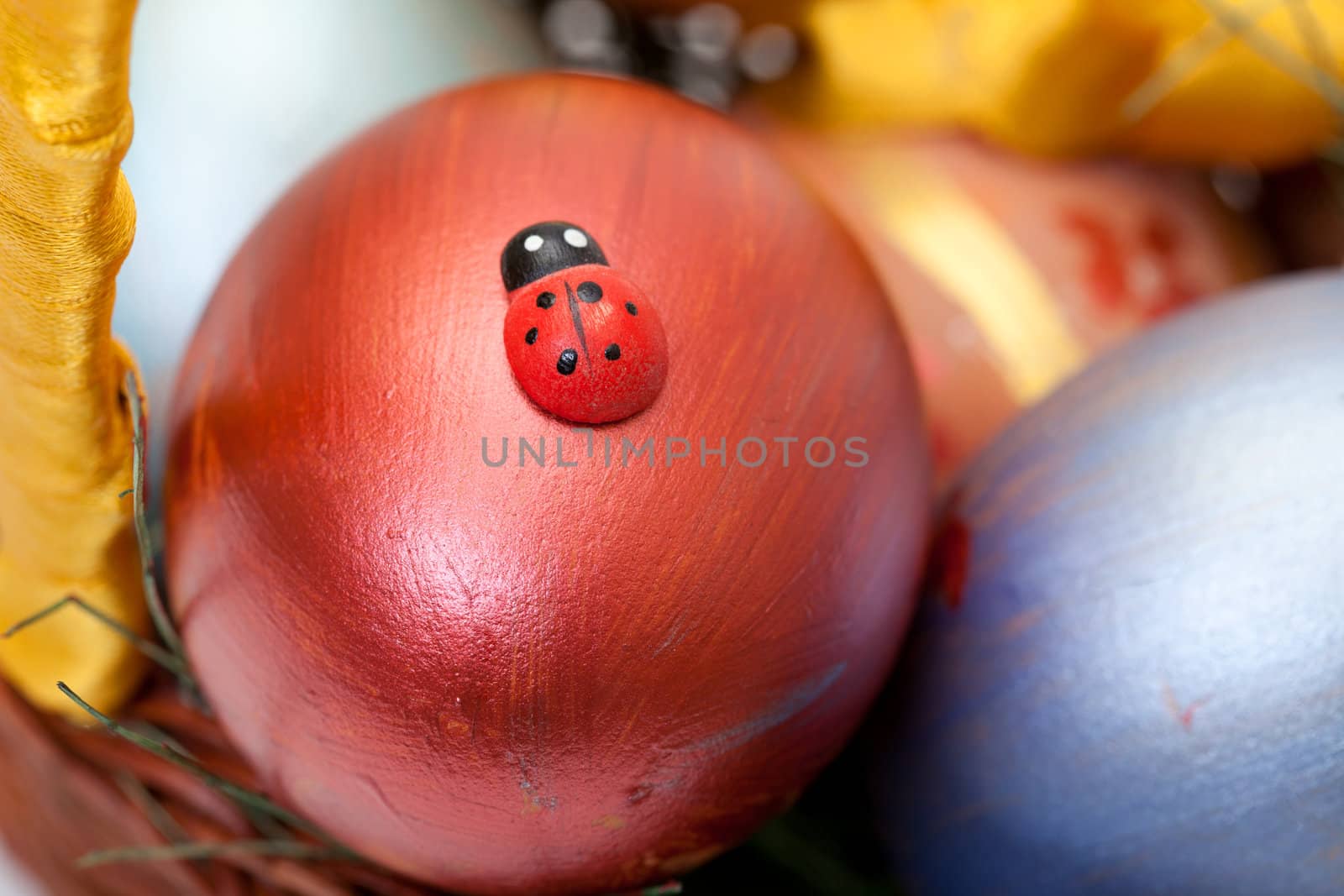 ladybug on painted easter eggs in basket, closeup