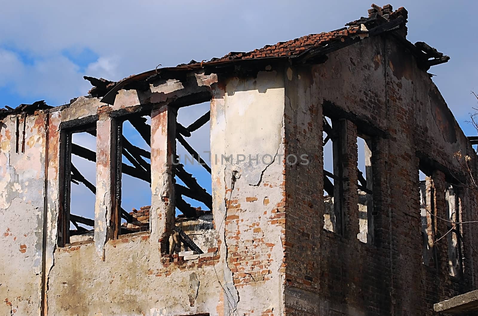 Burned old house, destroyed roof, blue sky