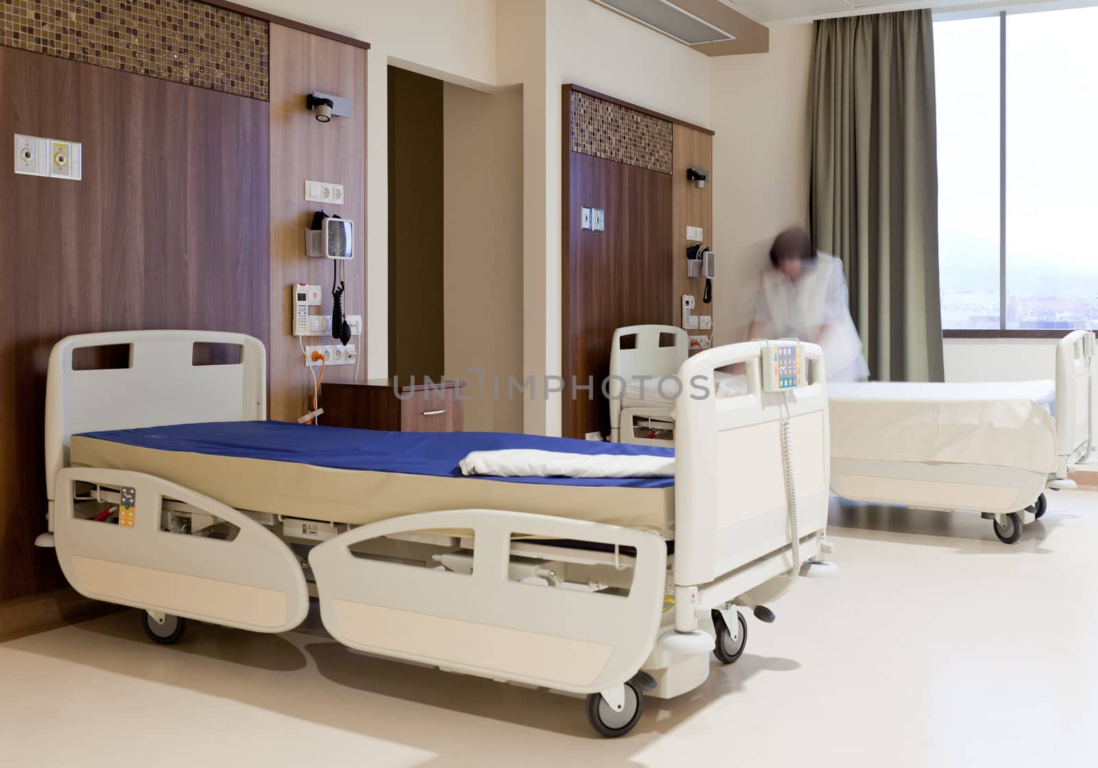 Blurred image of staff member in medical uniformn fixing hospital bed