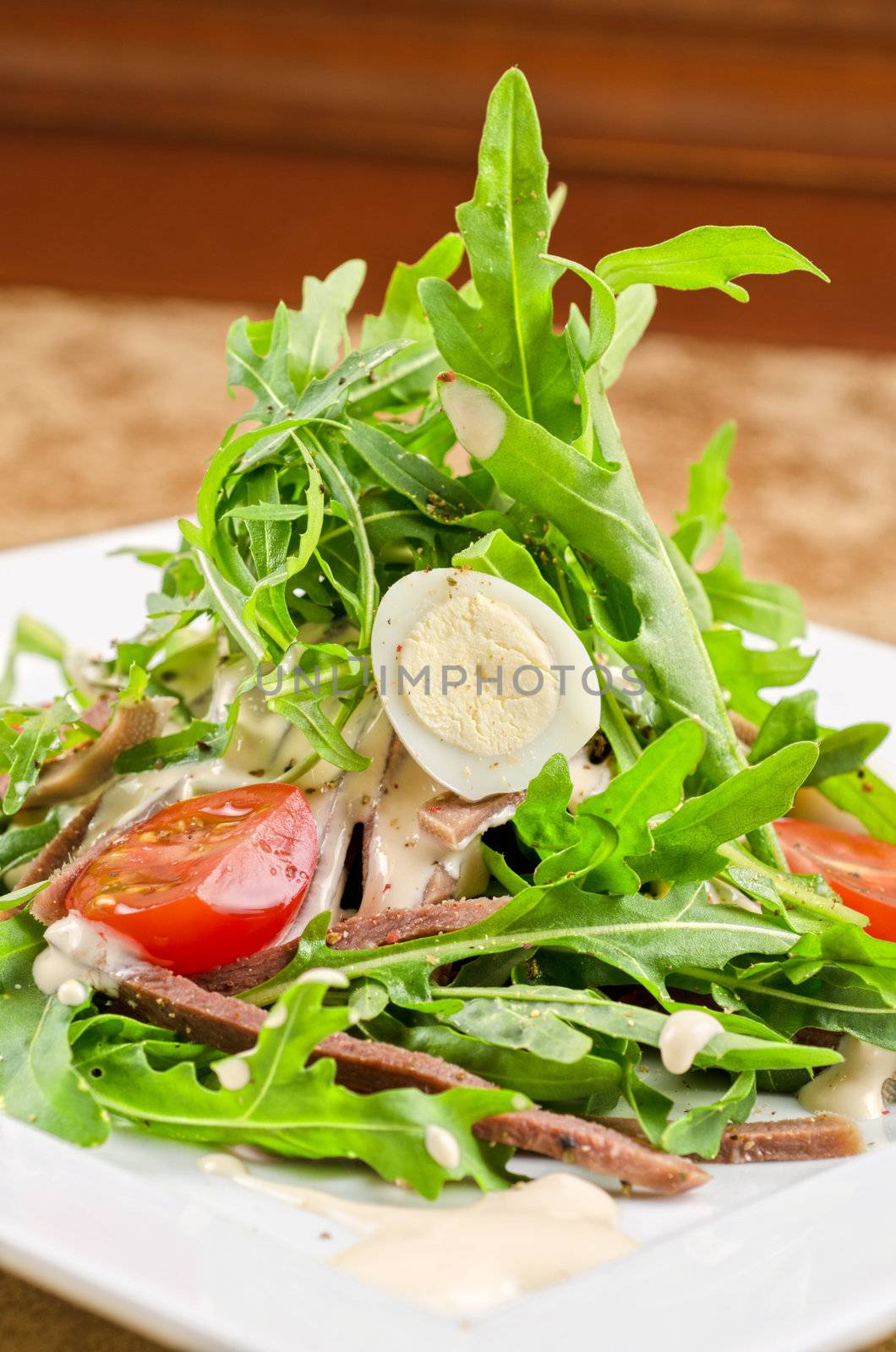 Tasty salad of beef tongue with eggs, arugula, tomato, spices and sauce