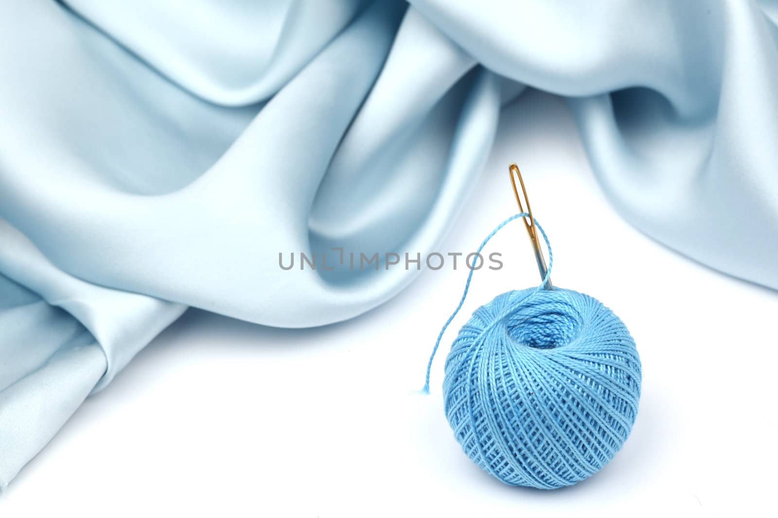 thread on blue silk isolated close up