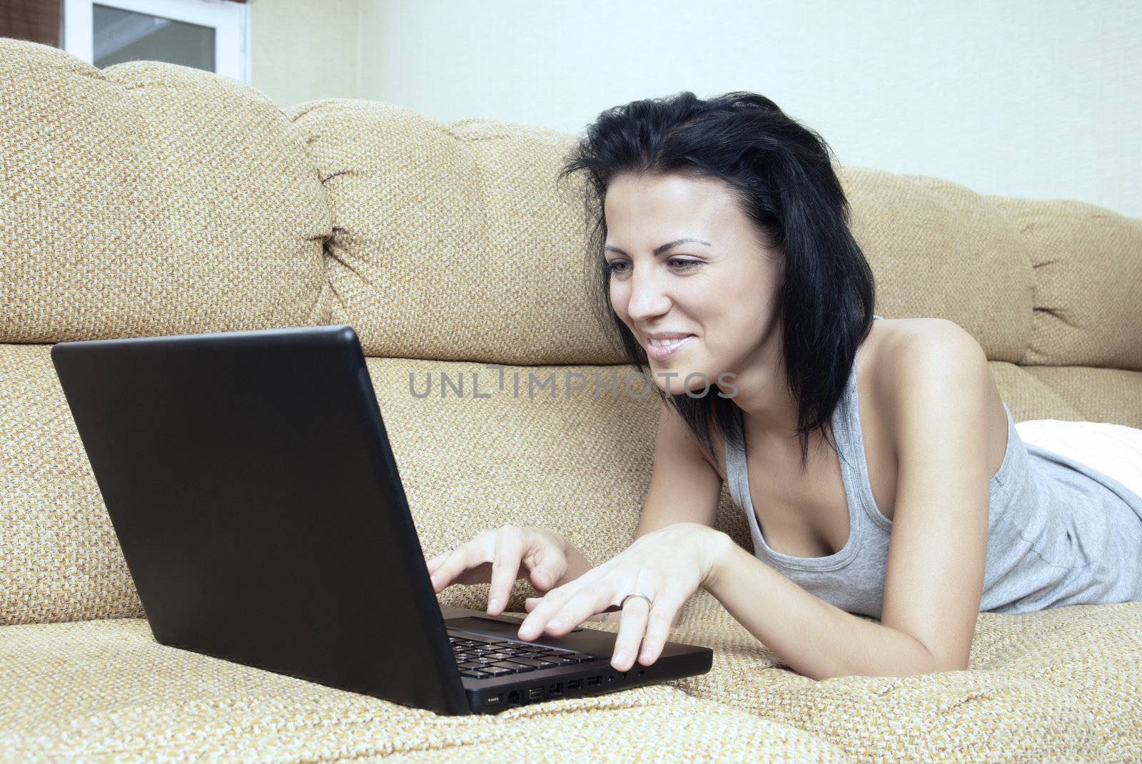Lady laying on sofa and using wireless notebook