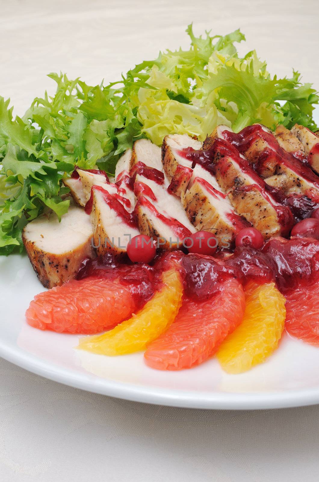 Sliced ​​baked fillet with cranberry sauce in lettuce leaves with orange and grapefruit