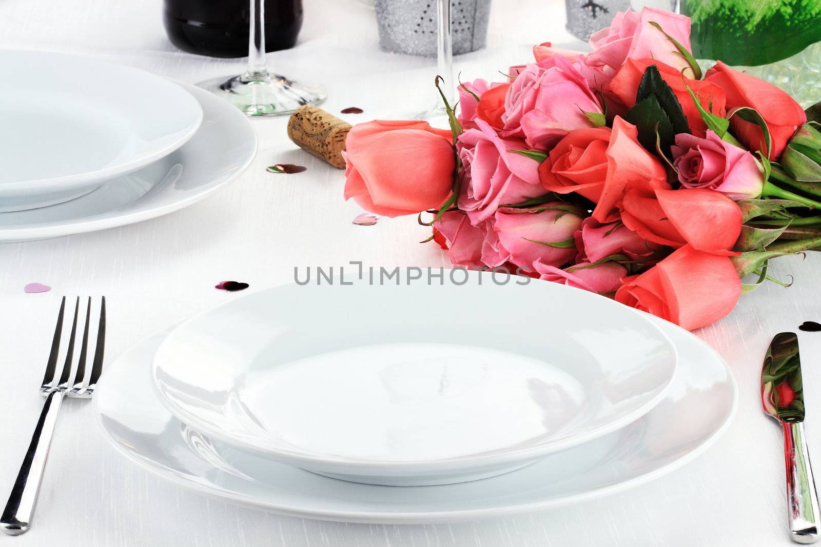 Romantic table setting for two with a bouquet of roses.