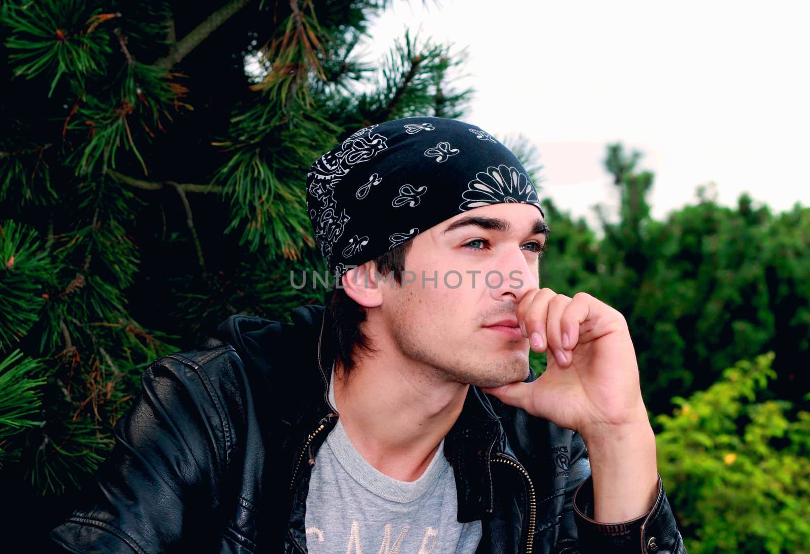 A handsome man in a bandana and a leather jacket in black with a hand from a person in thought