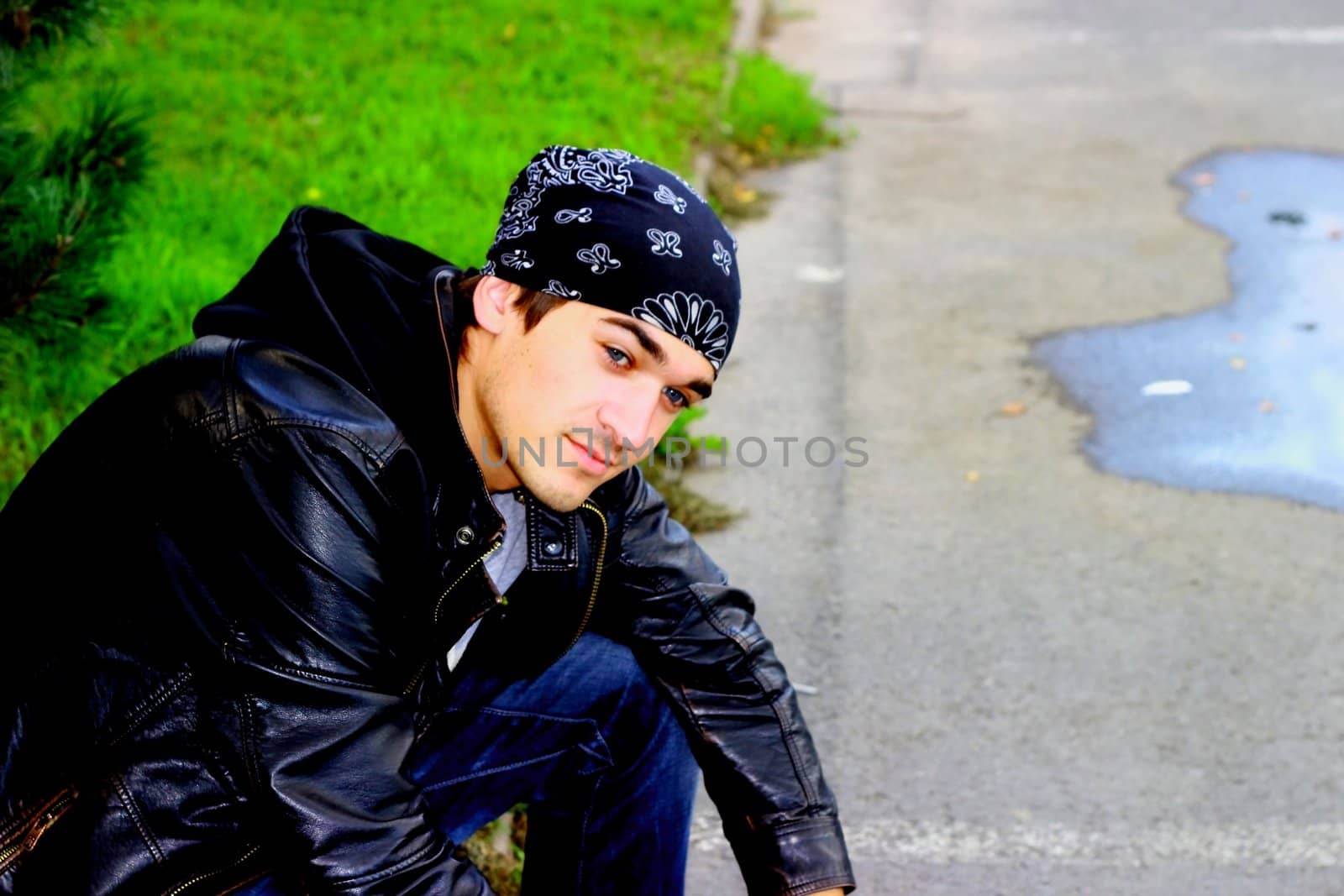 A handsome man in a bandana and a leather jacket in black with a hand from a person in joyful meditations