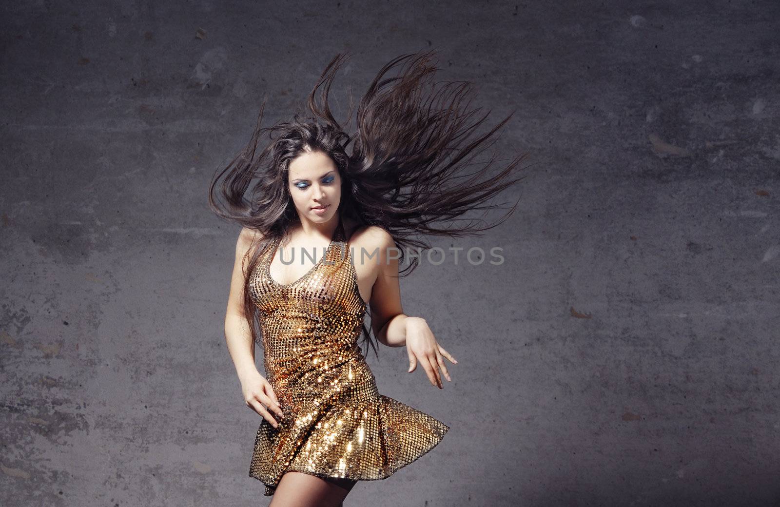 Active woman with long hair dancing on a trash background