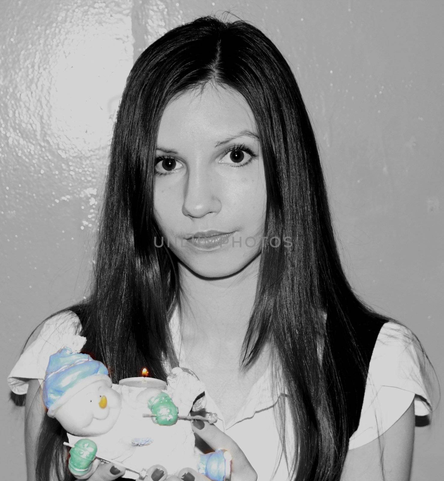 black and white photograph of a girl with a decorative snowman with burning candles