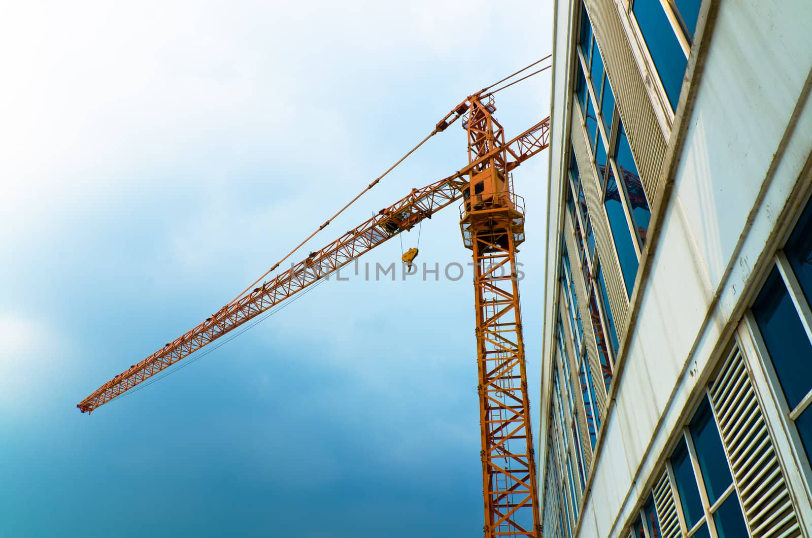 Orange crane lifting iron next to tall building