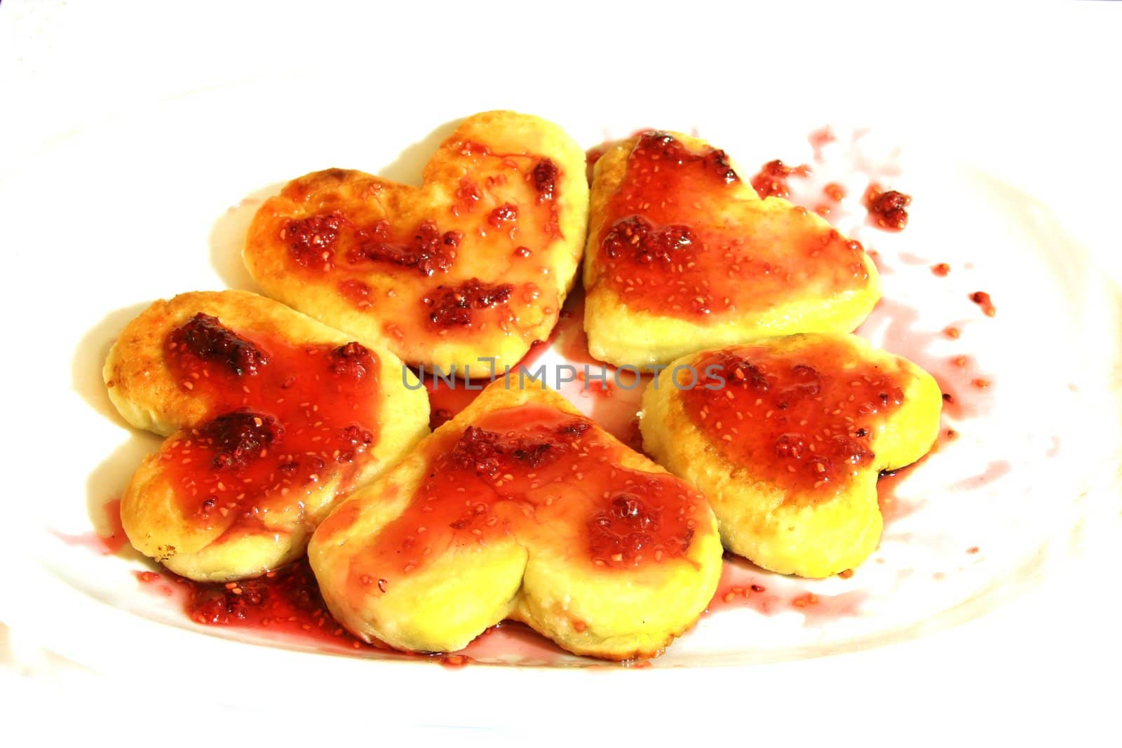 Cheese pancakes in form hearts.with arrow from srawberry jam Isolated on white background. Love