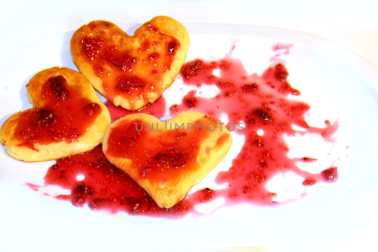 Cheese pancakes in form hearts.with arrow from srawberry jam Isolated on white background. Love