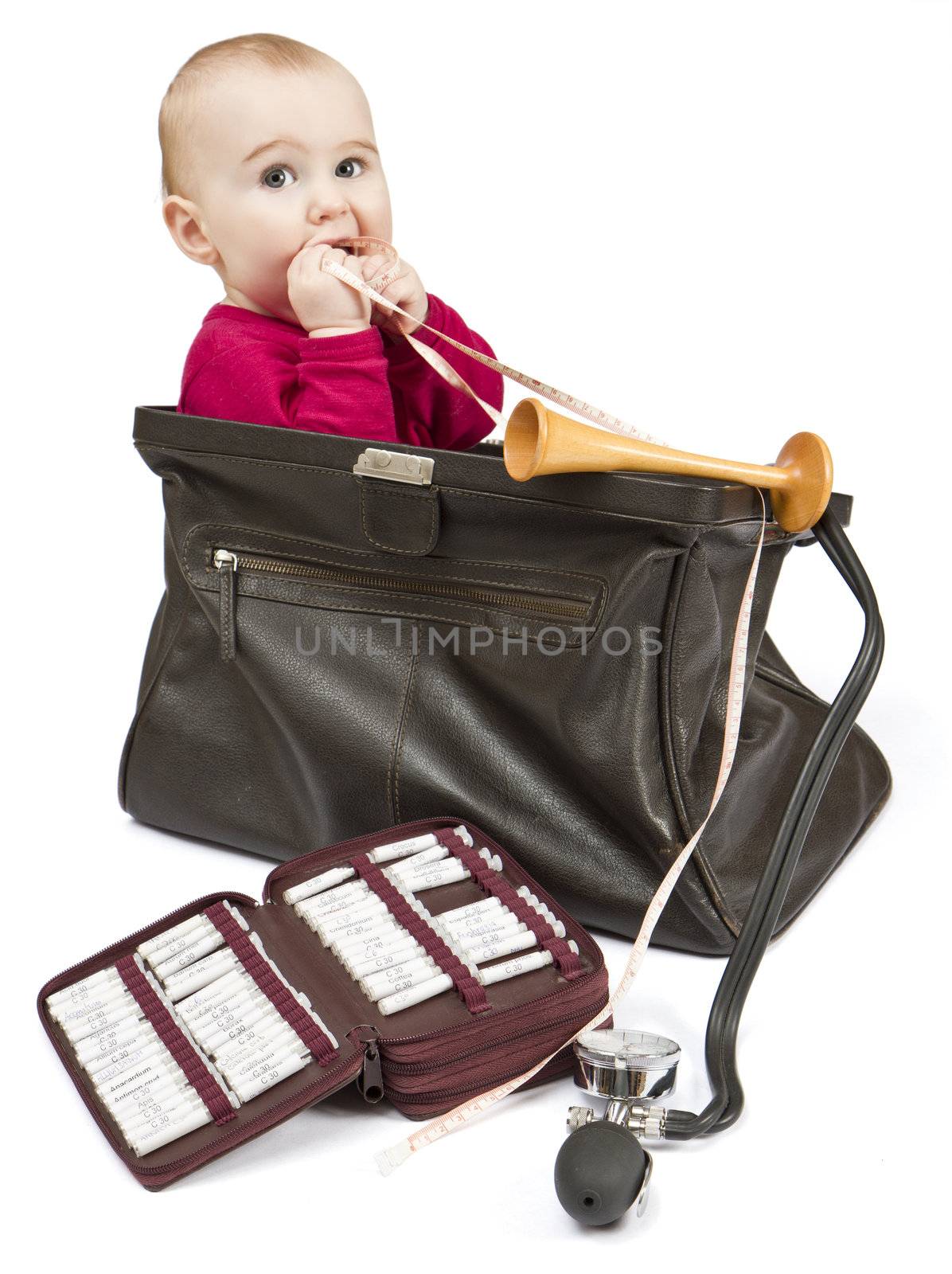 young child sitting in midwifes case with homeopathic globule , ear trumpet and measuring tape. No product names, just common names of homeopathic medicine.