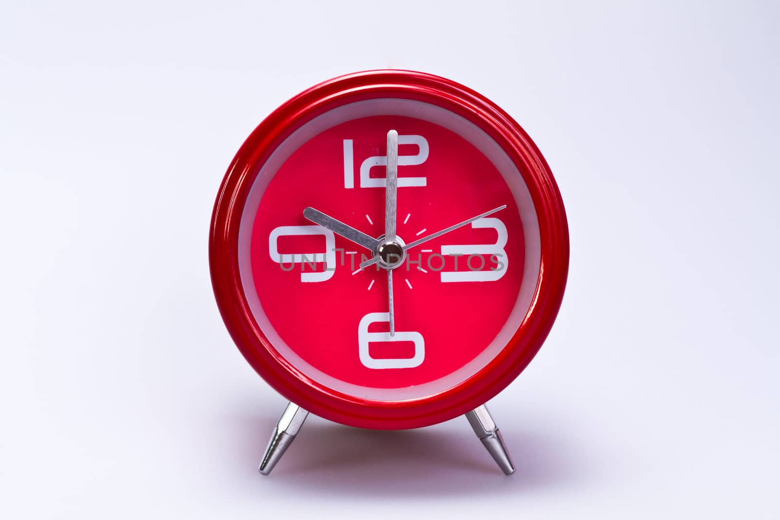 close up view of red clockface in the center of landscape orientation with shite background
