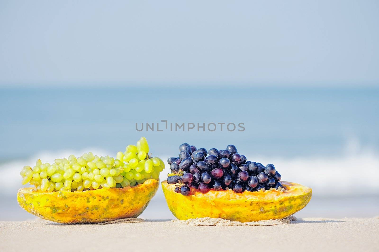 Papaya and grape on the tropical sandy beach