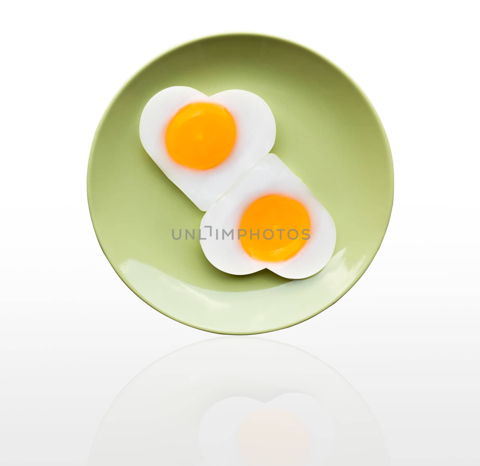 Fried egg heart on green dish on white background