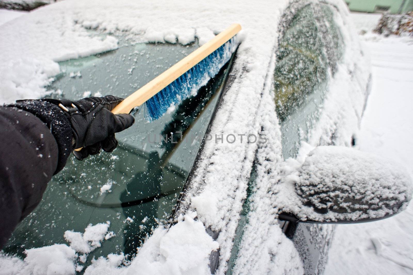 Removing snow from a car window using a brush