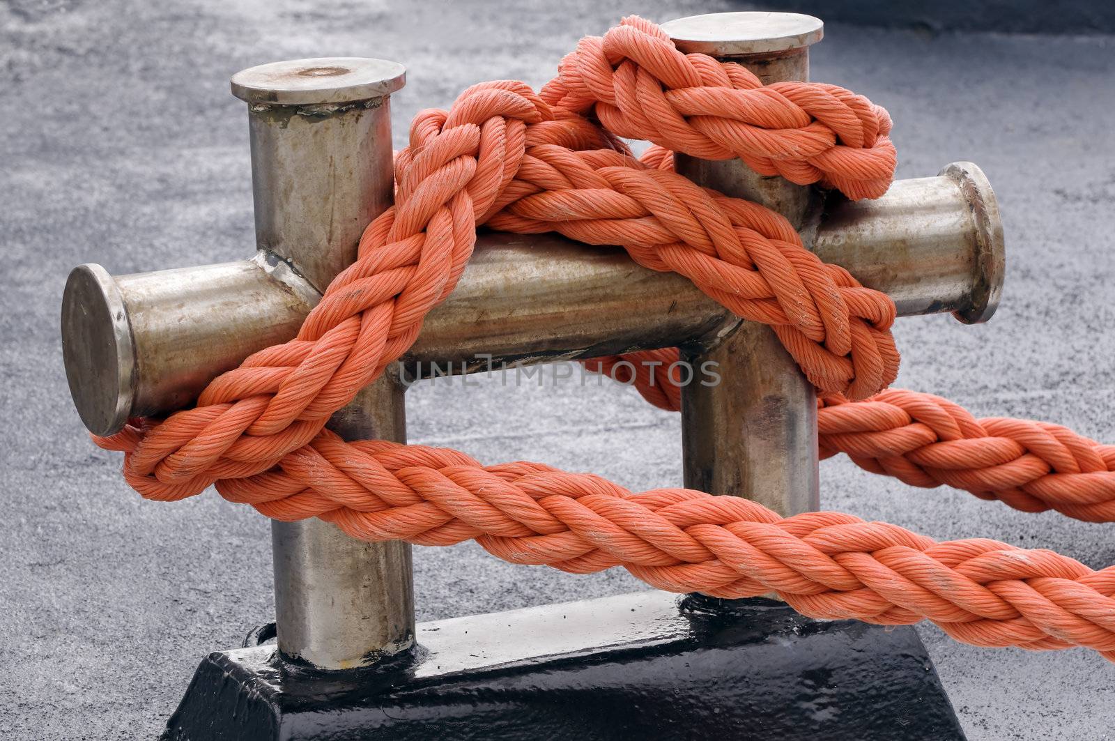 Close-up of an orange rope tied to a bitt